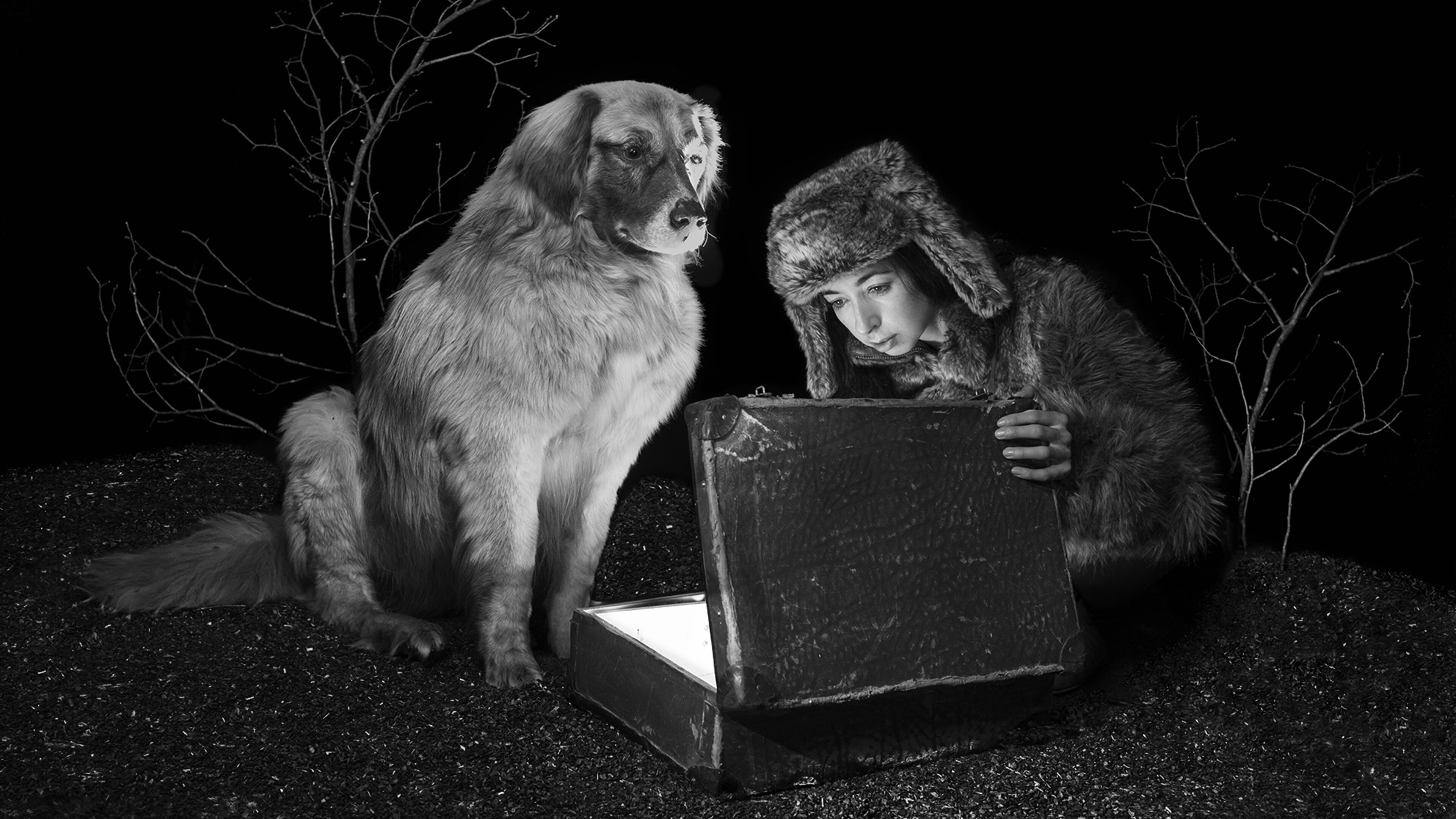 Black and white photography dog and woman looking into a suitcase