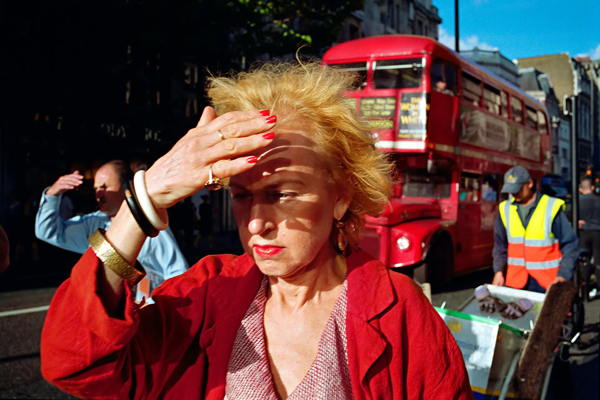Old woman with red jacket is blinded by the sun