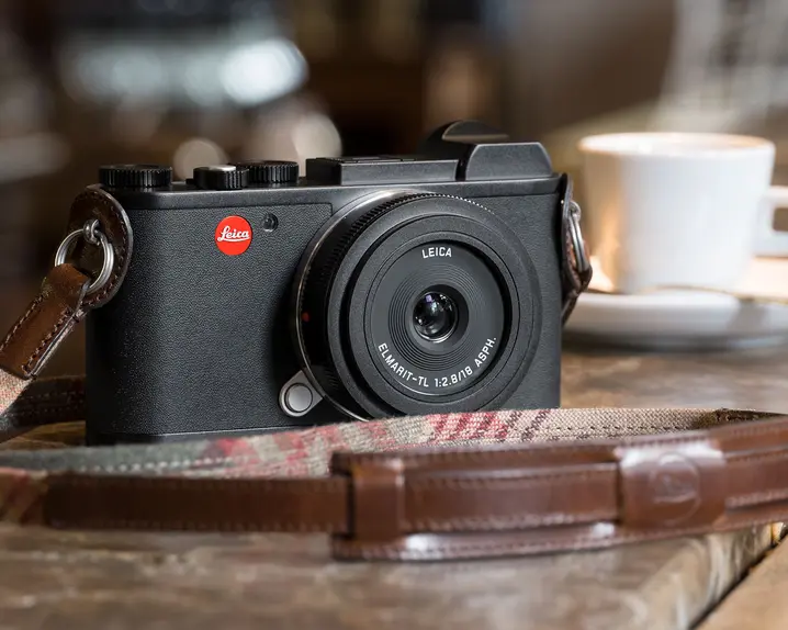 Leica camera on wooden counter with coffee cup in background