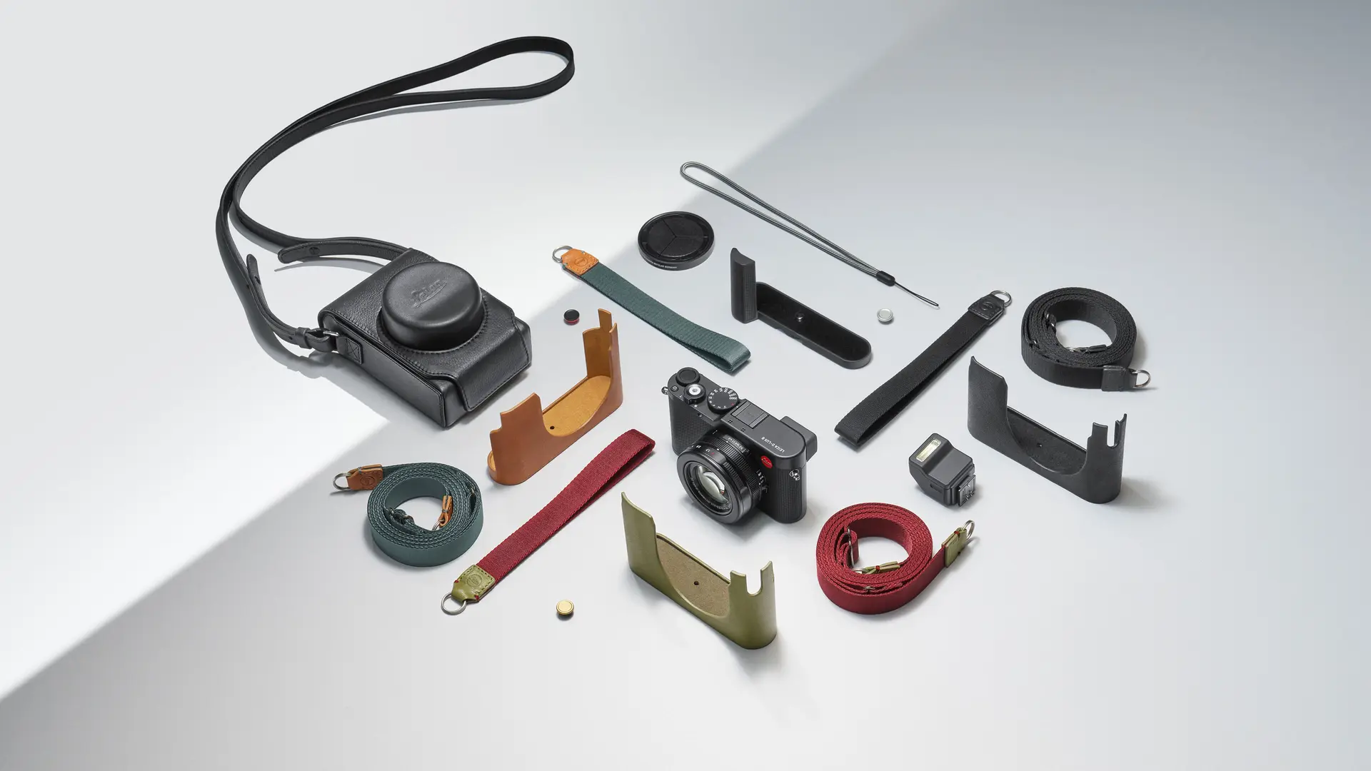 Leica camera with accessories such as straps and protective covers, on a light background