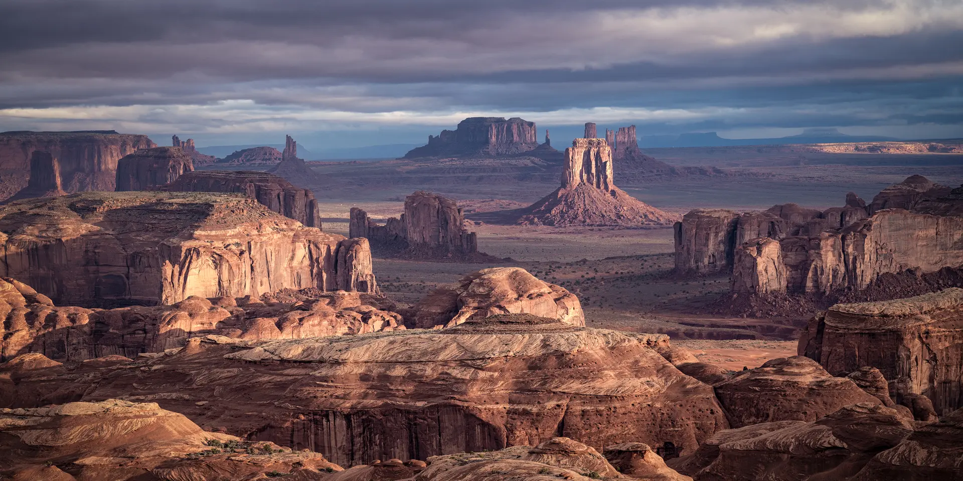 Vast desert landscape with remarkable rock formations under a cloudy sky.