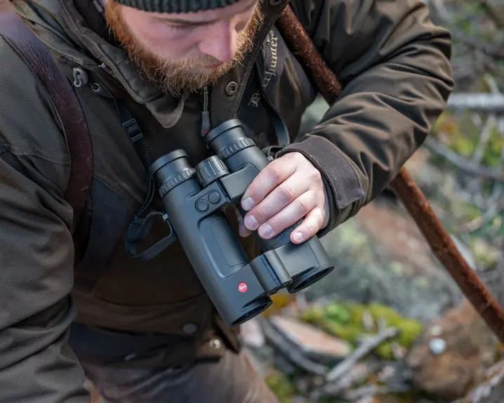 A Leica Geovid Pro is held by a hunter looking into the distance
