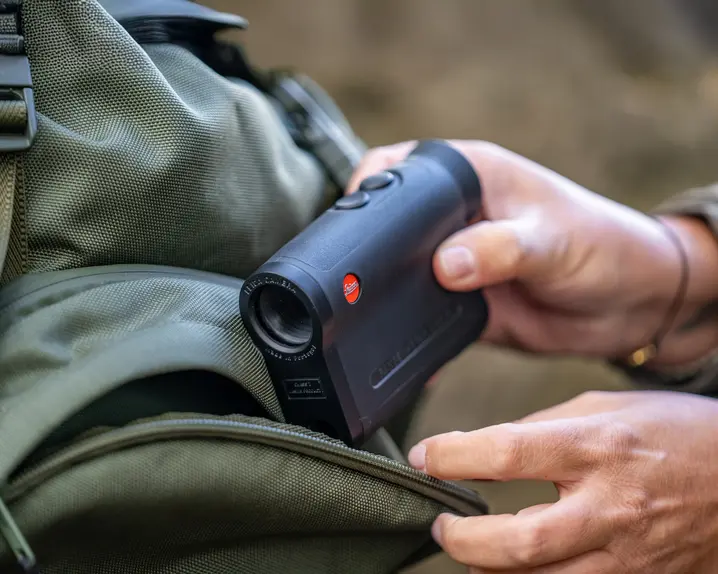 a person is pulling the Leica Rangemaster out of their bagpack