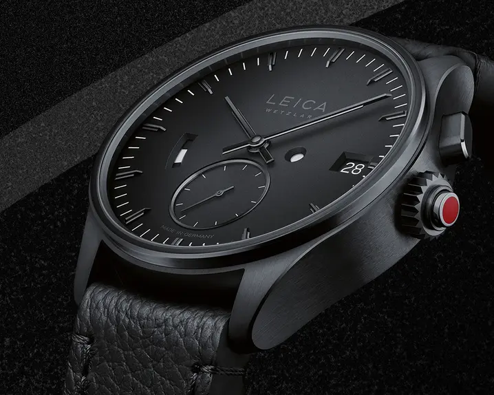 Close-up of a black Leica watch on a black background.