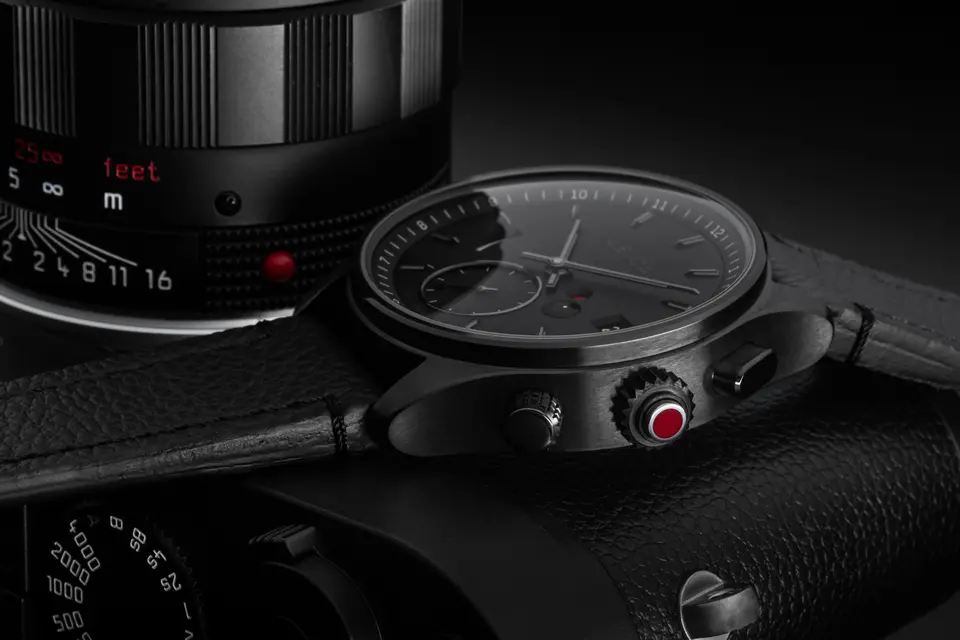Black leica watch with leica camera behind the watch