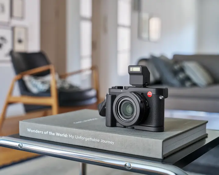 Leica D-Lux 8 placed on a book lying on a table.