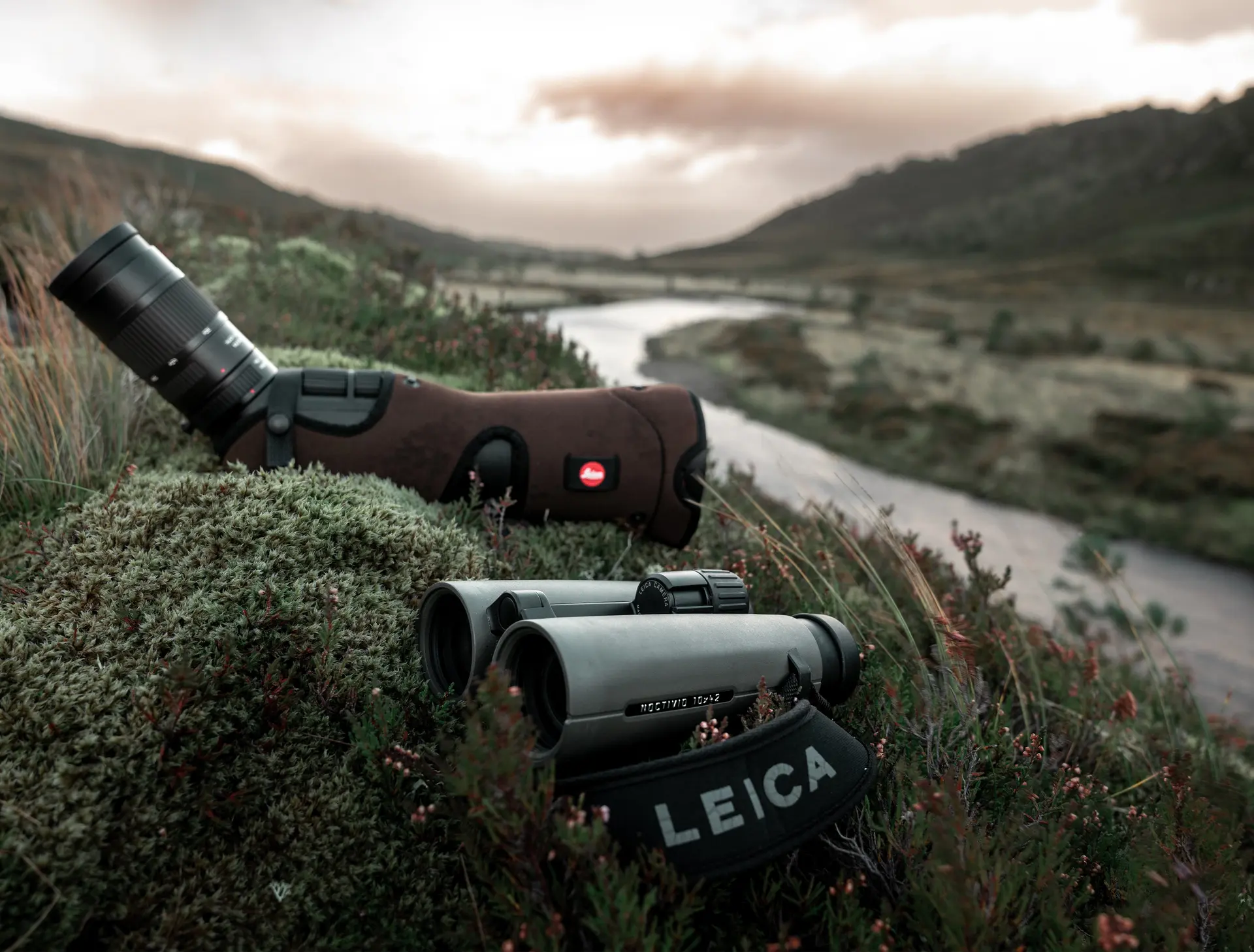 Leica-Noctivid-and-APO-Televid-lying-on-a-green-meadow-by-a-river
