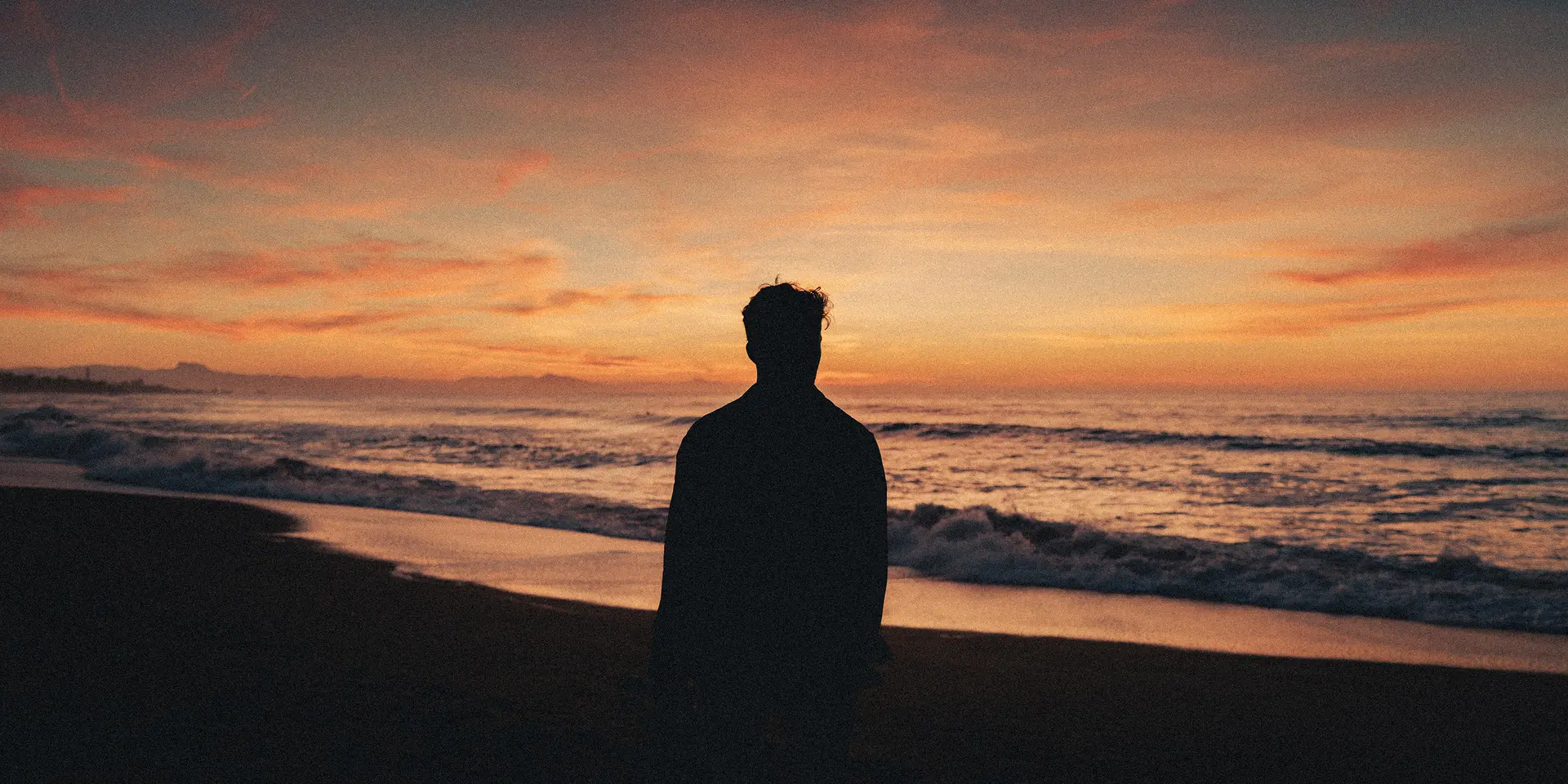 Silhouette of a man watching the sunset on the beach.