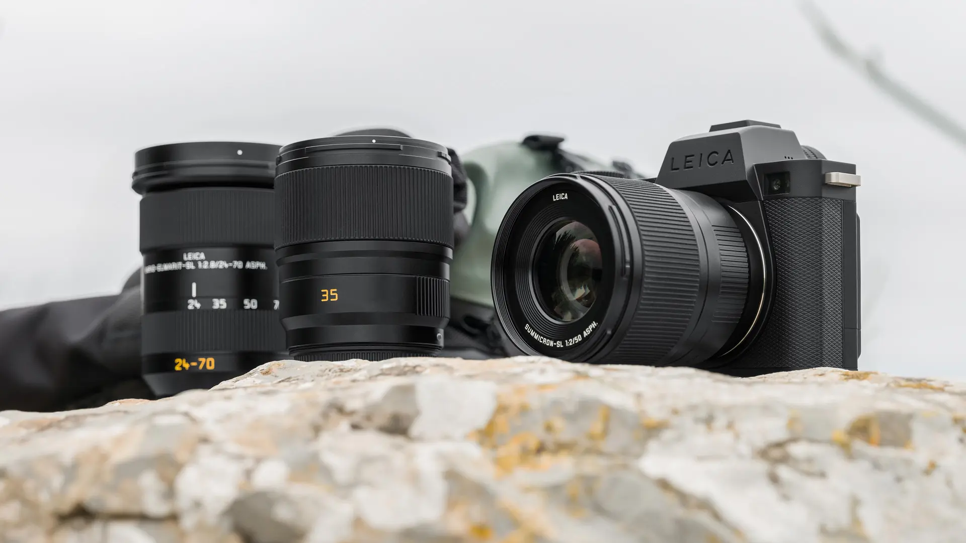 Leica cameras placed on a light-colored rock or stone with the sky in the background