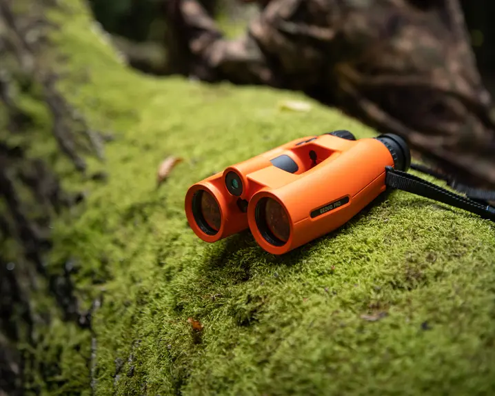 Leica-Geovid-Pro-Orange-lying-on-a-moss-covered-tree-trunk