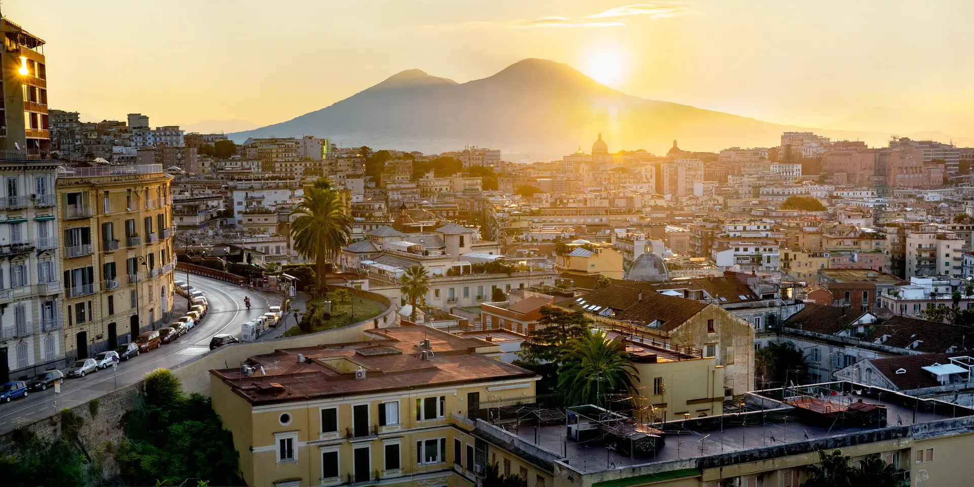 Italian city and the sun setting behind a mountain.