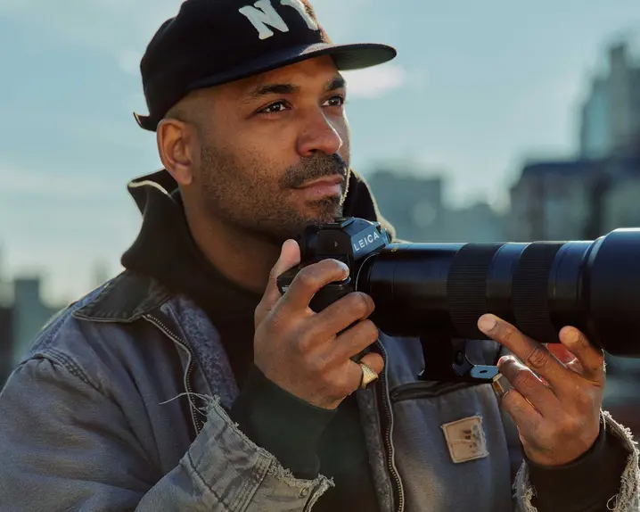 A young man is taking pictures with a cityscape in the background