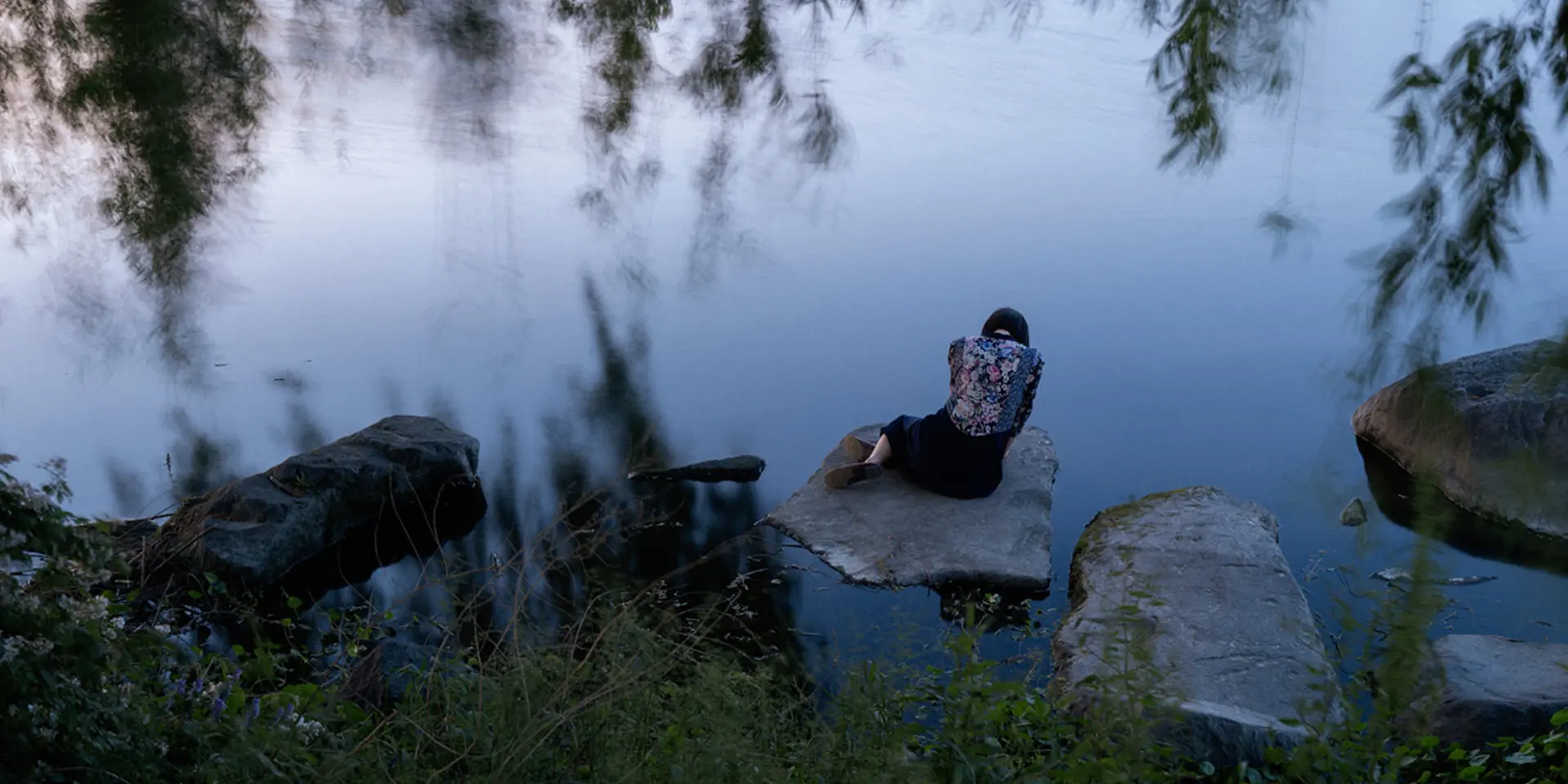Woman sitting on a stone by the lake