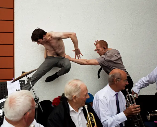 Group of men at a music event. Set on a brick and plain wall.